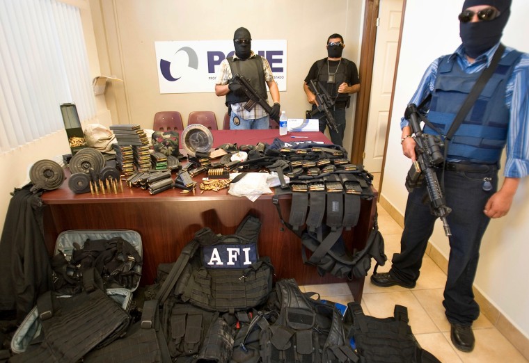 State police officers guard a seized arsenal during a presentation to the press in Rosarito, near Tijuana, Mexico, Wednesday, Oct. 1, 2008. A wave of apparent organized crime violence has swept Tijuana leaving behind 24 dead in the past 3 days.(AP Photo/Guillermo Arias)